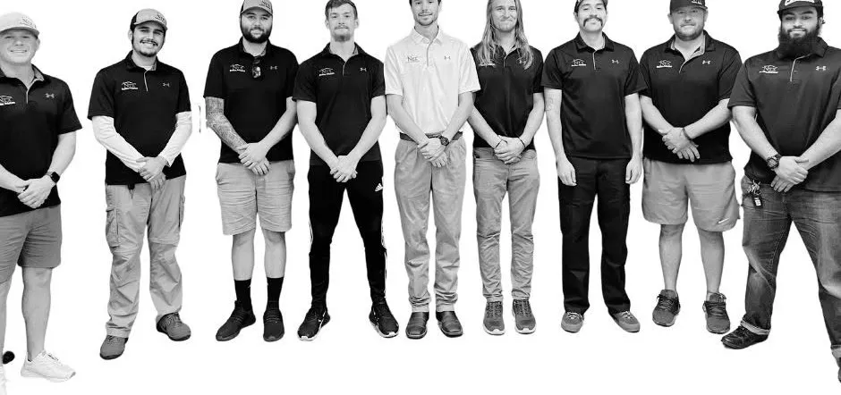 Nine members of the NTX Roofing Solutions team standing in a row in company shirts
